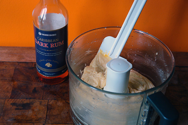 Almond cream in a food processor bowl with bottle of rum in the background | H is for Home