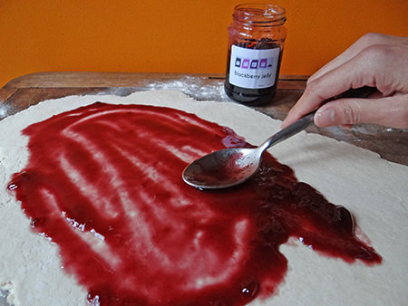 Adding jam to the rolled out roly poly pastry