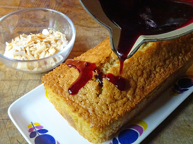 Pouring warmed fruit jelly over a freshly baked loaf cake
