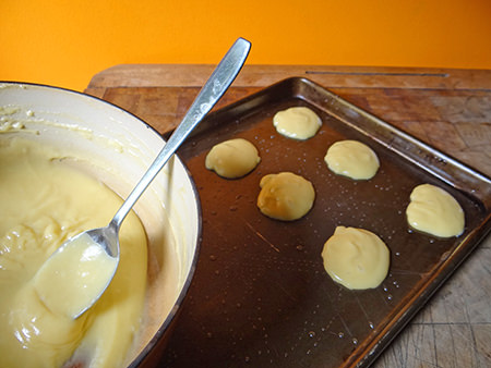 Profiterole batter rounds on a baking tray