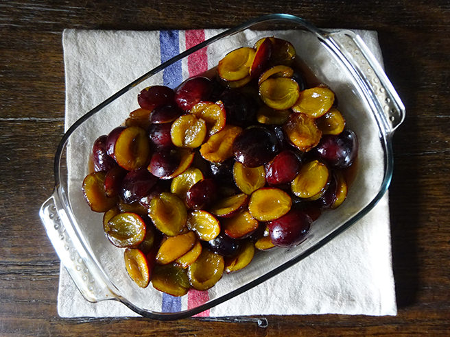 Cooked, spiced plums in a clear Pyrex casserole dish