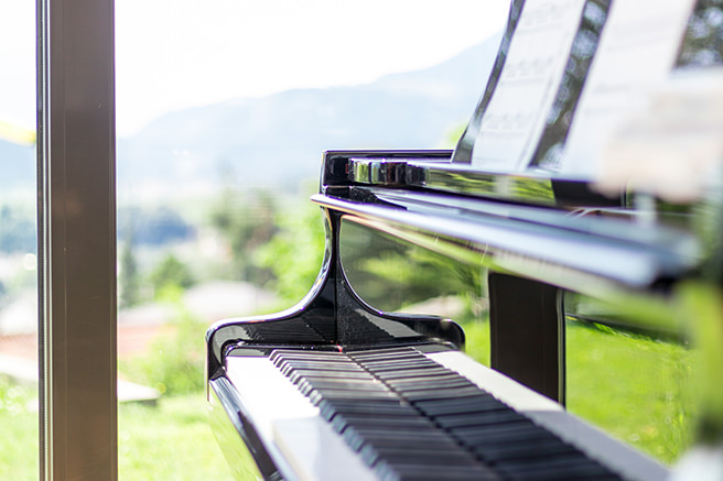 Piano next to a window looking out to a graden
