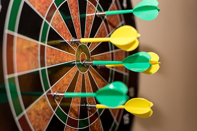 Green and yellow darts on a darts board