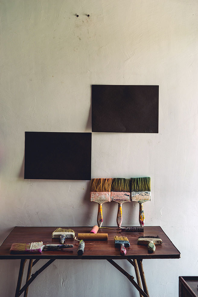Paintbrushes leaning against a pale wall