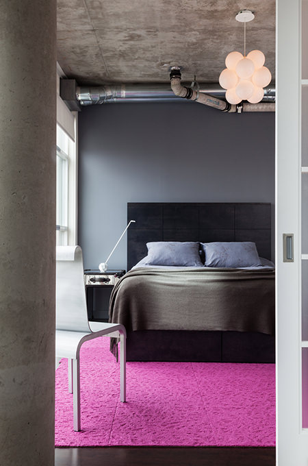 Bedroom decorated in shades of grey with bubble gum pink rug