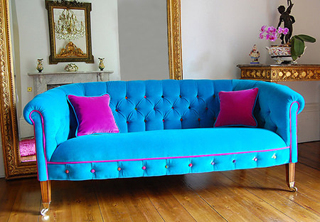 Turquoise upholstered sofa with bubblegum pink trim and cushions