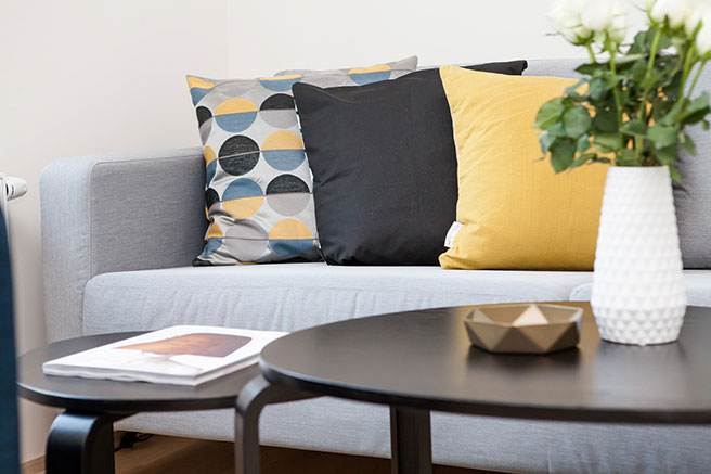 Black, yellow and grey cushions on a grey sofa