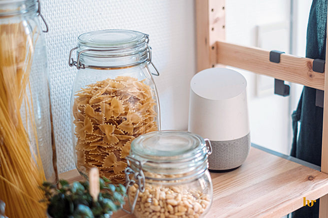 Wooden shelf with jars of pasta and Google smart speaker