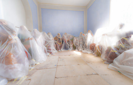 bubble wrapped mannequins sitting on the floor in an empty room
