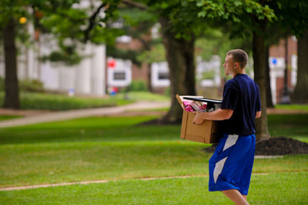 young man moving a cardboard box full of stuff