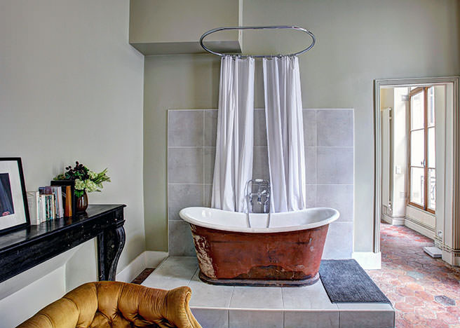 Sage green pained bathroom with copper bath and gold sofa