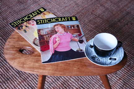 vintage 1950s palette topped teak table with splayed legs with Ridgeway Homemaker tea cup & saucer and two vintage 1950s Stitchcraft magazines