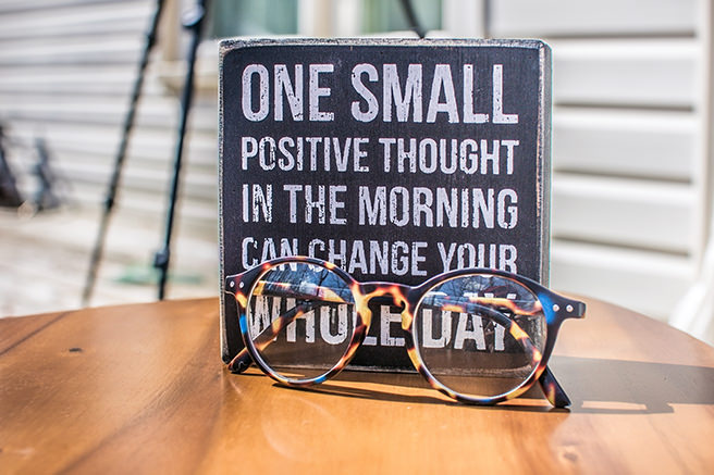 Positive thought table sign with pair of glasses