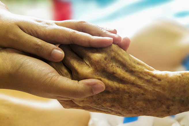 Hands holding the hand of and elderly person
