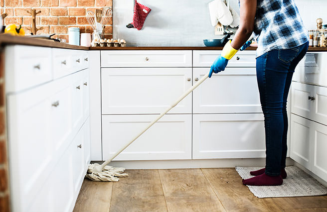 Woman mopping a wooden kitchen floor