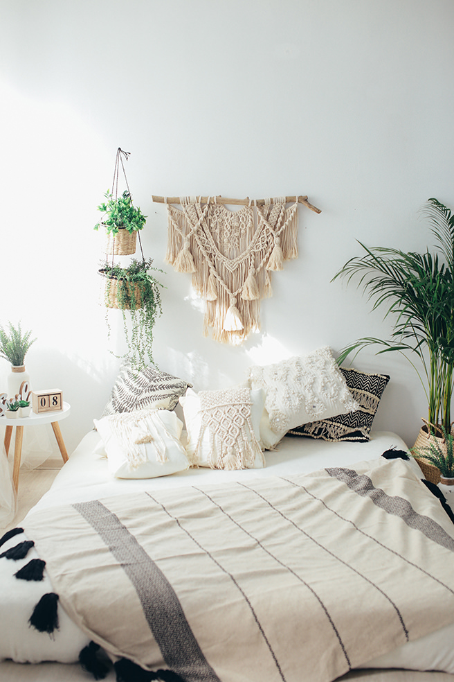 Natural macramé wall hanging with macramé cushions on the bed beneath