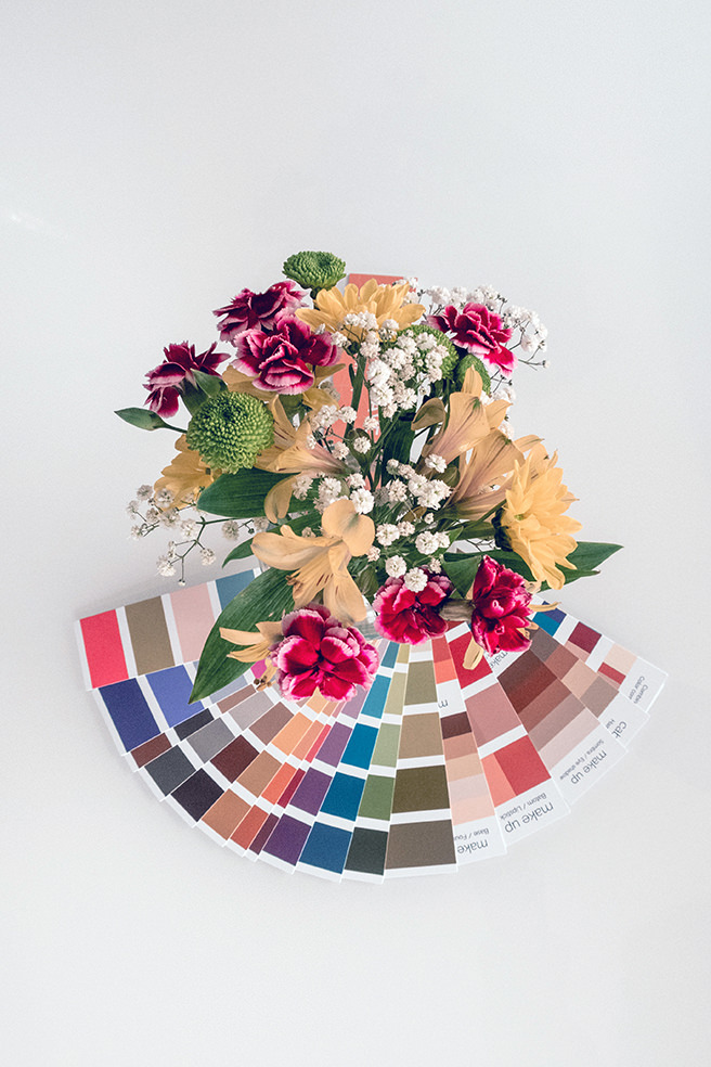 Fan of colour chips with vase of flowers