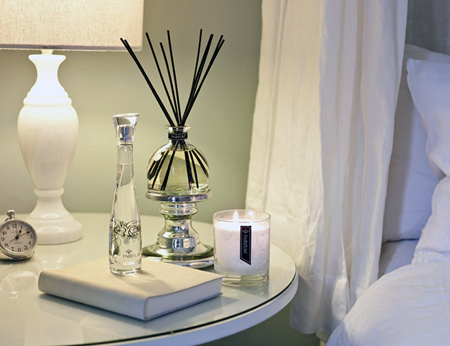Scented candle and reed diffuser on a bedside table